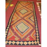 A Persian woollen Kilim rug, the red ground decorated with three lozenge medallions within a