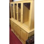 A contemporary light elm side cabinet, having four glazed upper doors with adjustable panelled