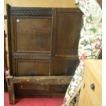 An antique panelled oak double half tester bed, having relief carved and panelled headboard with