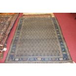 A Turkish woollen rug, the blue ground decorated with rows of geometric gul motifs within trailing