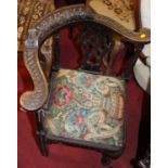 A 19th century floral relief carved oak corner elbow chair with floral upholstered drop-in pad