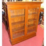 An early 20th century stained pine double door bookcase on raised plinth, width 130cm