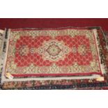 A Persian woollen red ground rug, 60 x 103cm (worn); together with four other small Persian and