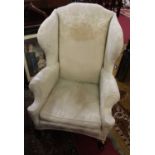 A circa 1900 mahogany framed and cream floral upholstered wingback scroll armchair, raised on