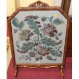 A figured walnut framed and floral tapestry embroidered fire screen having carved floral surmount,