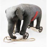 An early 20th century Steiff pull-along elephant, in grey felt, with glass eyes and button to ear,