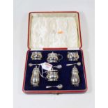 A George V silver six piece cruet set to include a pair of mustards, each with blue glass liner,