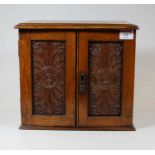 An Edwardian oak smokers cabinet, having a hinged lid above a pair of panelled doors, opening to