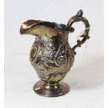 A 19th century silver cream jug of helmet shape having repoussee floral decoration and flying C-