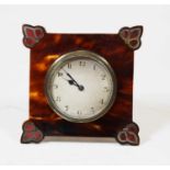An early 20th century tortoise shell framed travel clock of square form, the proud corners inlaid