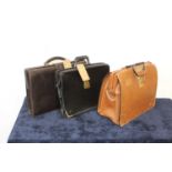 A gent's tan leather satchel with combination lock; together with two black leather examples (3)