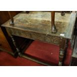 An antique joined oak plank top side table, having floral relief carved frieze and raised on ring