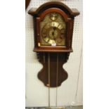 A reproduction mahogany droptrunk wall clock, having a brass arched dial, three weights and