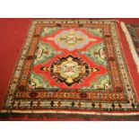 A Turkish woollen red ground rug, having bright coloured geometric floral central ground within