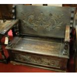 An early 20th century floral relief carved oak fold over monks bench, having a typical hinged box