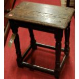 An antique joined oak joint stool raised on ring turned square cut supports, united by lower