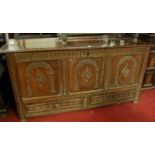An 18th century joined and chip carved oak three panelled hinge top mule chest, having twin short