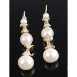 A pair of yellow metal, pearl and diamond drop earrings, each with three graduated freshwater