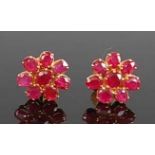 A pair of yellow metal ruby flower cluster earrings, each comprising eight oval faceted rubies in