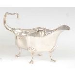 An Edwardian silver cream jug, of shaped oval form, the top with a reeded edge, all raised on paw