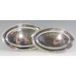 A graduated pair of Mappin & Webb silver meat dishes, each of oval form with reeded raised rims,