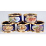 A set of five porcelain napkin rings, each decorated with an oval vignette, to include pheasant,