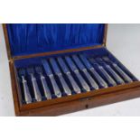 A cased 12-place setting of George V silver cake knives and forks, the handles each engraved with
