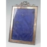 An Edwardian silver photograph frame, having ribbon surmount, engine turned border, and velvet bound