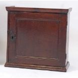 An antique oak wall cupboard, the panelled door opening to reveal a fitted interior of nine drawers,