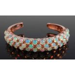 A rose metal torque bangle, comprising three rows of hydrophane opal cabochons, 41 in total,