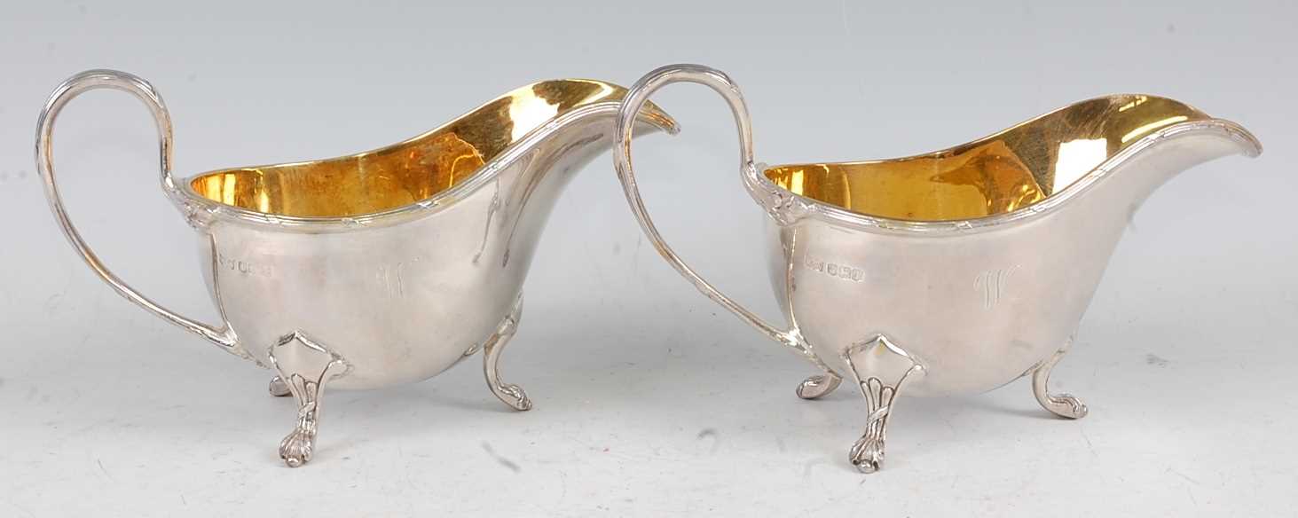 A pair of Mappin & Webb silver sauceboats, each having gilt-washed interiors, reeded edges, and on