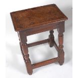 An 18th century oak joint stool, the top having a moulded edge above a moulded frieze, on turned and