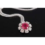 A white metal, ruby and diamond daisy shaped cluster pendant, comprising a centre round faceted ruby