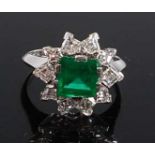 A white metal, emerald and diamond rectangular cluster ring, featuring a centre step cut emerald