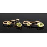 A pair of yellow metal peridot drop earrings, each featuring an oval and a round faceted peridot,