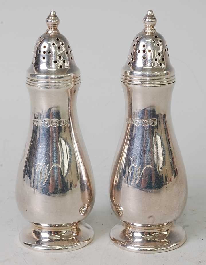 A pair of Mappin & Webb silver pepperettes, having pierced and domed screw tops over slender