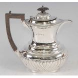 An Edwardian silver hot water pot, of half-reeded oval bombe form, having ebony handle, 11.8oz,