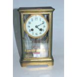 A late 19th century lacquered brass cased four glass mantel clock, having a circular enamel dial