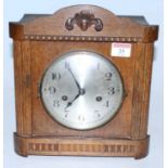 A 1930s oak cased mantel clock having a silvered dial with Arabic numerals and eight day movement,