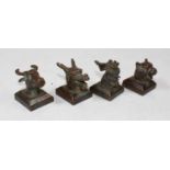 A set of four modern Chinese bronze desk seals, each surmounted with an animal's head, comprising