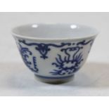A small Chinese porcelain blue and white tea bowl, having asymmetric decoration and four character