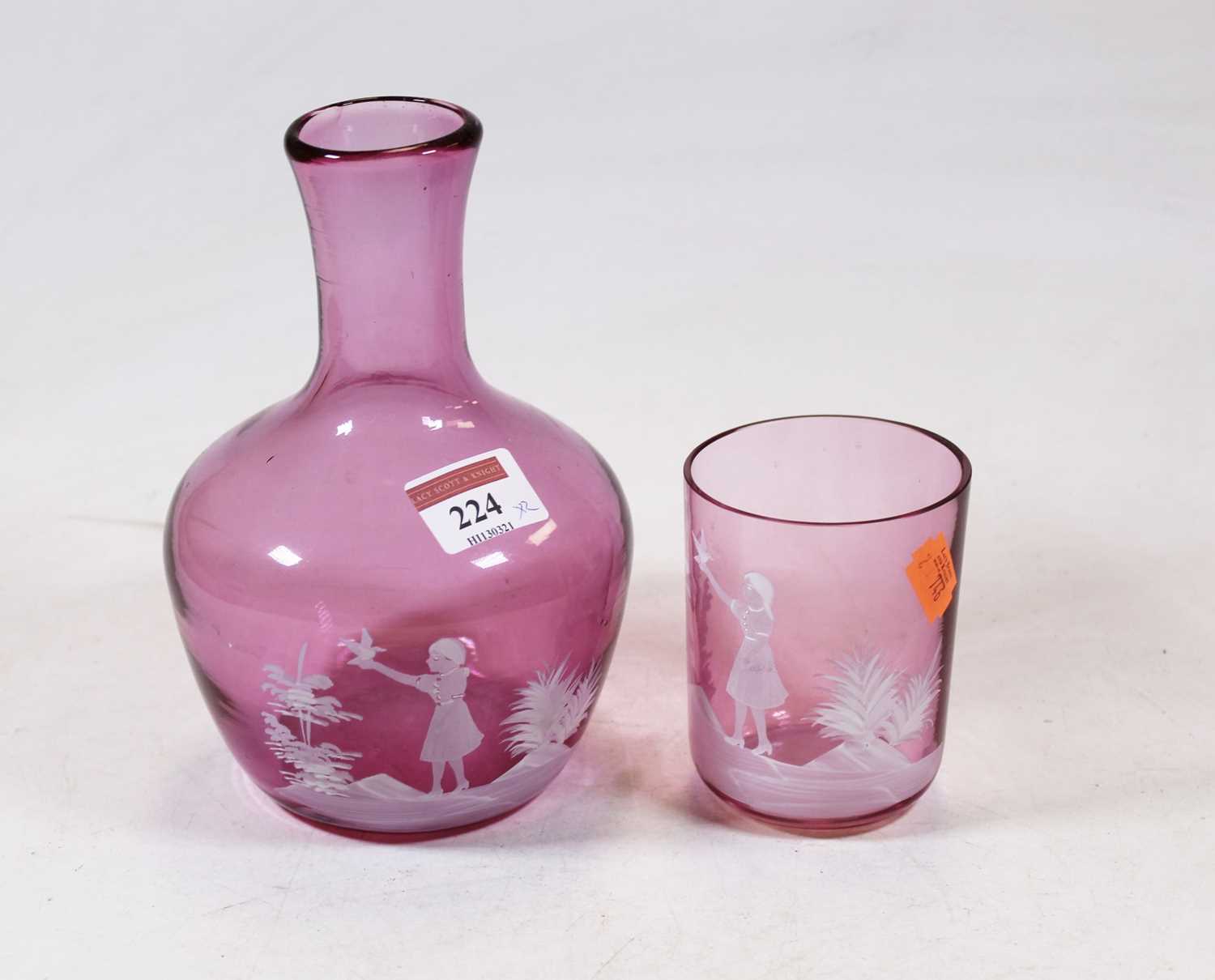 An amethyst tinted glass carafe with Mary Gregory style decoration in the form of a girl with bird