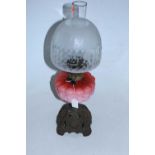 A Victorian pedestal oil lamp having a domed glass shade above a pink tinted font on pierced cast