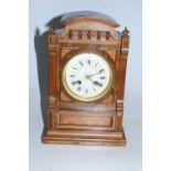 A late Victorian walnut cased mantel clock of architectural form having a circular dial with