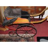 A late Victorian pram, having part-painted ash and pine coachwork, leather upholstered seat and