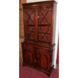 A reproduction mahogany and flame mahogany bookcase cupboard, having twin astragal glazed upper