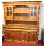 A contemporary stained pine kitchen dresser, the upper section having open central shelves flanked