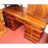 A contemporary stained pine twin pedestal writing desk, having typical arrangement of nine