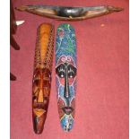 Two South East Asian carved soft wood elongated face masks, together with a further model boat (3)