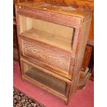 A 1930s limed oak three-tier stacking book case, having two glazed hinged panel doors, and one